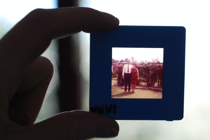 Two fingers hold the frame of a picture. This older photo shows a man and a woman.