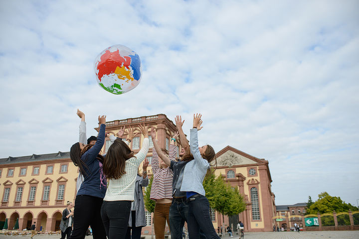 Eine Gruppe von Studierenden wirft im Ehrenhof eine aufgeblasene Weltkugel in die Luft.