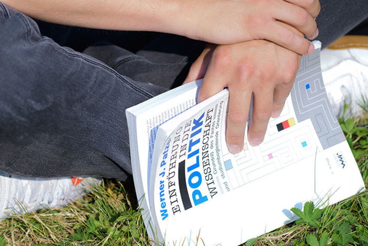 Bild zeigt sitzende Person mit Buch in Händen