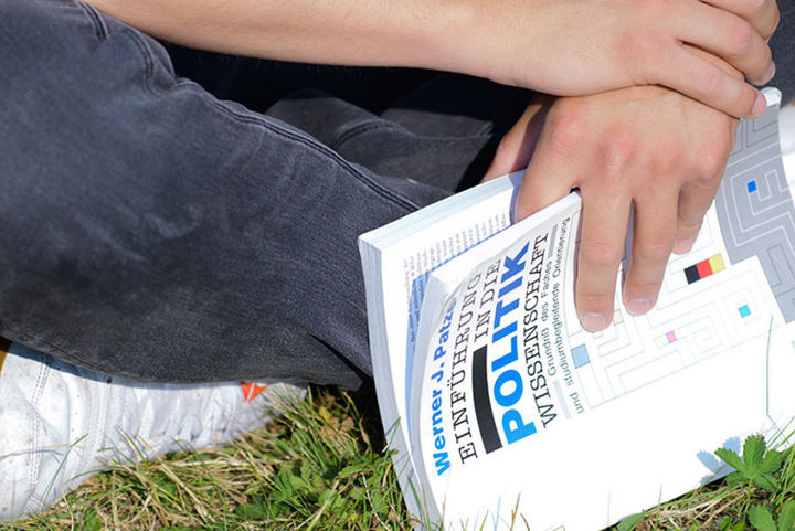 Bild zeigt sitzende Person mit Buch in Händen