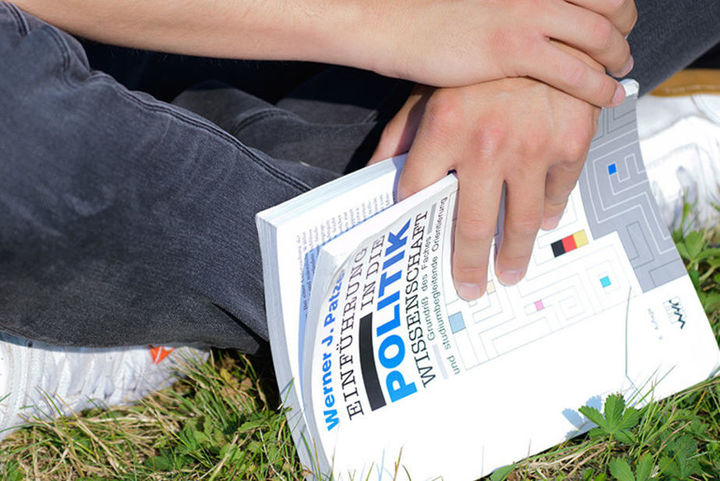 Bild zeigt sitzende Person mit Buch in Händen